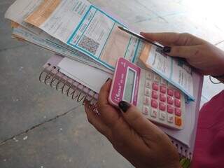 Consumidora, com calculadora, tentando negociar dívida no Procon Municipal, em março (Foto: Izabela Cavalcanti)