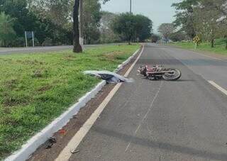 Corpo da vítima coberto e moto caída na via após acidente. (Foto: O Pantaneiro)