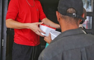 Funcionário distribui marmitas aos moradores de rua, sempre no horário combinado com Flávia (Foto: Paulo Francis)