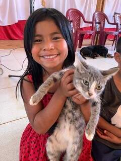 Menina indígena segura gatinho cinza enquanto espera atendimento da Subea itinerante na Aldeia Água Bonita. (Foto: PMCG)