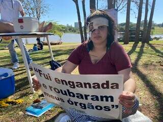 Mulher interpreta pessoa que teve as córneas retiradas e segura cartaz (Foto: Thailla Torres)