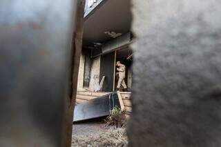 Pela fresta é possível ver bombeiro saindo e parte da parede queimada (Foto: Henrique Kawaminami)