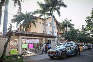 Viatura da Polícia Militar e cartazes pregados no portão do condomínio (Foto: Henrique Kawaminami)