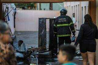 Bombeiro e moradores no local com pertences queimados. (Foto: Henrique Kawaminami)