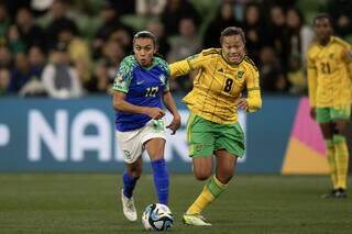 Marta, de uniforme azul, tenta escapar da forte marcação jamaicana (Foto: CBF)