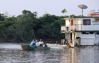 Pescadores em lancha, perto de barco-hotel que dá suporte aos turistas. (Foto: Divulgação)
