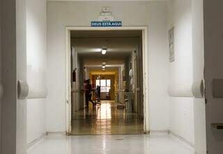 No corredor de enfermaria da Santa Casa, aviso indica que além de profissionais de saúde, Deus cuida de pacientes (Foto: Juliano Almeida)