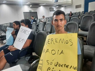 O repositor Thiago Pereira da Costa (à dir.) segura cartaz no plenário da Câmara Municipal (Foto: Caroline Maldonado)
