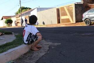 Criança sentada na calçada observando a rua (Foto; Arquivo/Campo Grande News)
