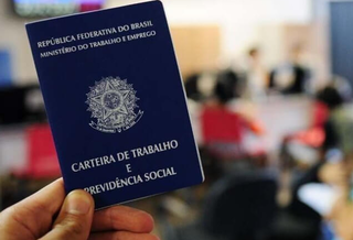 Trabalhador apresenta carteira de trabalho em fila por vagas de emprego.