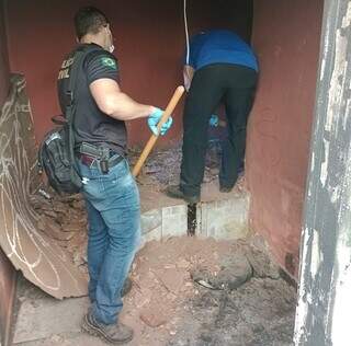 Policiais civis cavando cama de concreto onde ossada foi encontrada. (Foto:Divulgação/Polícia Civil)