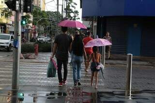 Casal e criança com guarda-chuva, na Rua 14 de Julho (Foto: Arquivo/Campo Grande News)