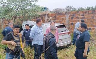 Policiais brasileiros e paraguaios ao lado de Sportage encontrado em terreno baldio (Foto: Divulgação)