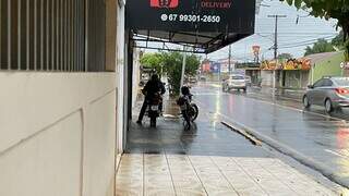 Motociclista esperando a chuva passar em marquise na Rua Brilhante (Foto: Antonio Bispo)