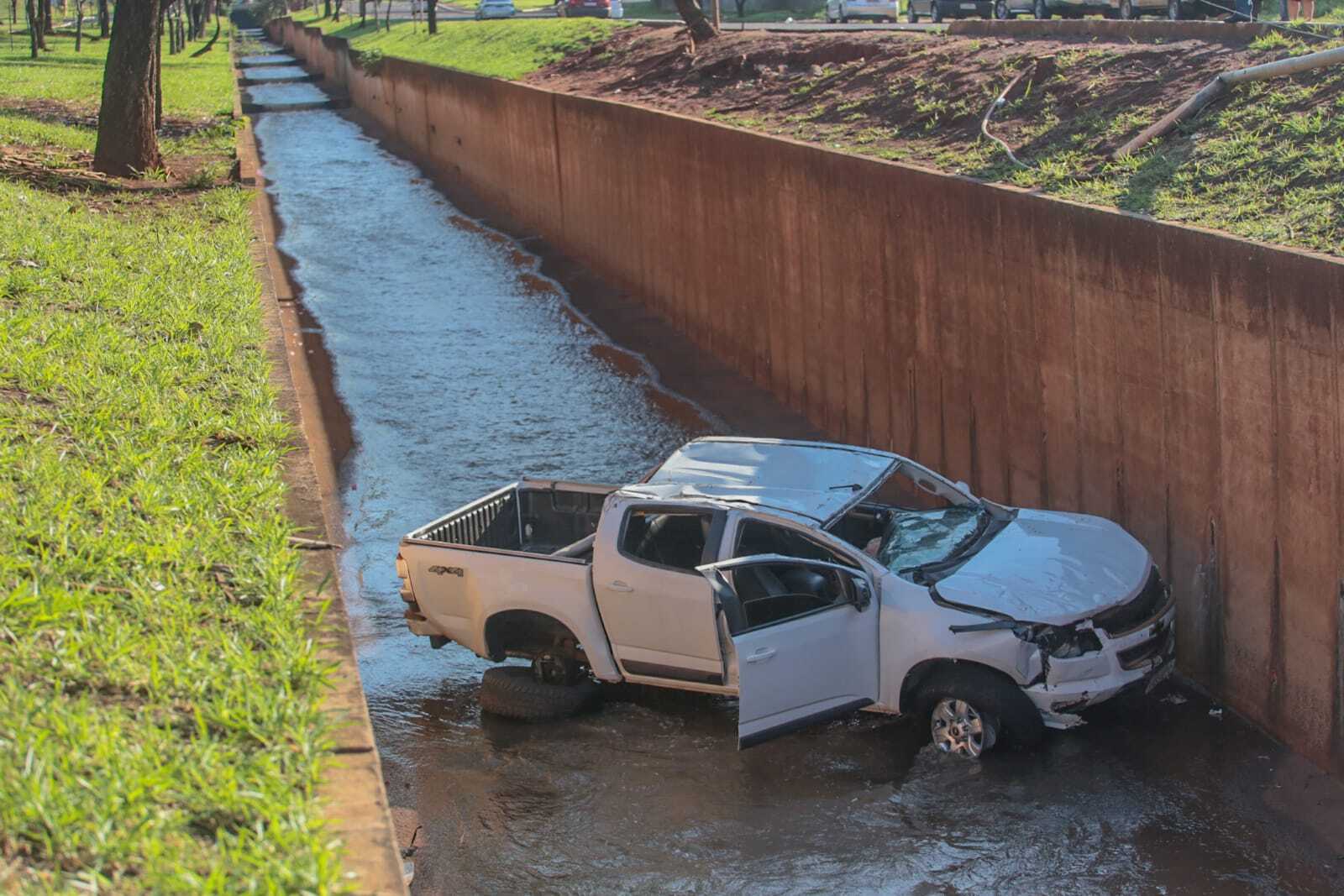 Motorista perde controle em rotat&oacute;ria e cai com camionete dentro de c&oacute;rrego 