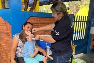 Agente da Sesau realiza imunização em criança, em escola de Campo Grande (Foto: Divulgação)