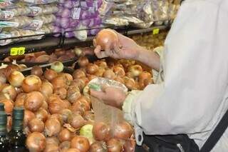 Mulher seleciona cebolas em mercado de Campo Grande (Foto: Campo Grande News/Arquivo)