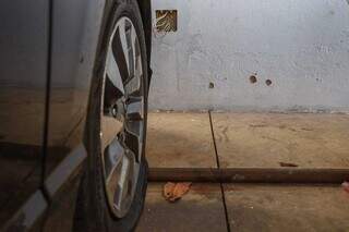 Pneu do carro furou com os tiros e disparos acertaram a parede da casa. (Foto: Henrique Kawaminami)