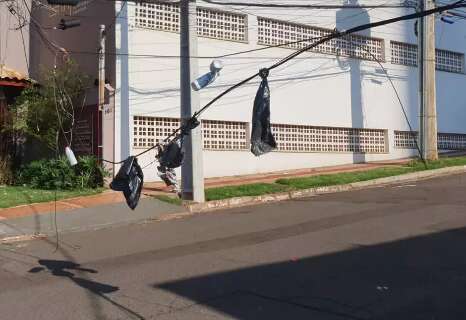 Moradores improvisam sinalização com sacos amarrados em "varal" de fios caídos