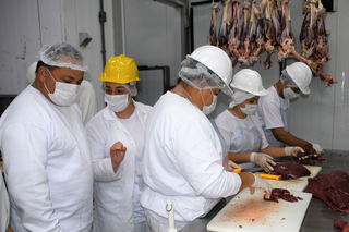 Funcionários de um frigorífico realizam cortes na carne, preparada em Campo Grande. (Foto: Reprodução/PMCG)