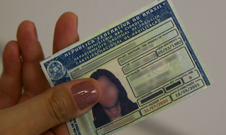 Motorista habilitada para conduzir carros segura documento oficial de identificação. (Foto: Marcelo Casal Jr./Agência Brasil)