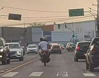 Passageiro de motocicleta segurando capacete na frente da placa (Foto: Direto das Ruas)