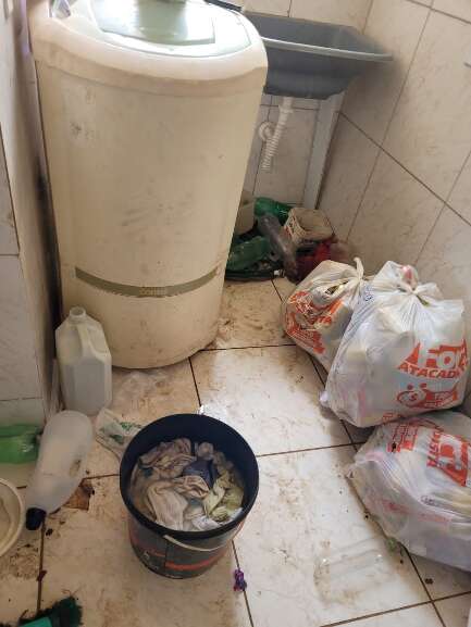 Lixo, sujeiras e balde com roupas de molho entre a lavadeira e cozinha do local (Foto: Divulgação | GCM)