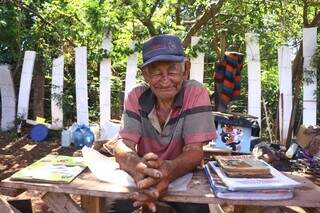 Seu José e os livros que passa o dia a ler na mesinha feita por ele. (Foto: Paulo Francis)