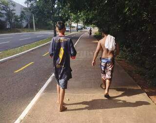 Crianças saem de Córrego Sóter e caminham na Avenida Nely Martins, região norte de Campo Grande (Foto: Alison Silva)