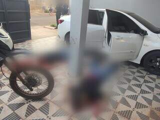 Dois corpos ao lado de Chevrolet Onix, na garagem da casa onde quatro foram mortos (Foto: Direto das Ruas)