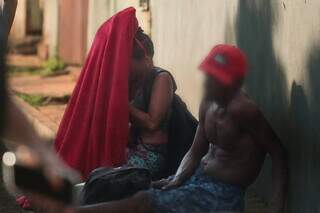 Mulher cobre a cabeça com cobertor, para usar drogas ao lado de homem que acabou de acordar. (Foto: Marcos Maluf)