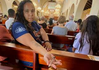 Juliana mostra caneta abençoada durante missa, no Santuário Perpétuo Socorro, em Campo Grande (Foto: Antonio Bispo)