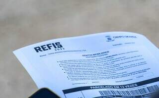 Contribuinte de Campo Grande segura boleto de pagamento enviado no primeiro Refis de 2023. (Foto: Juliano Almeida/Arquivo)