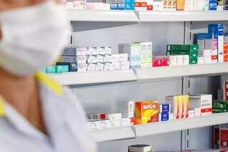 Atendente em farmácia, com remédios dispostos ao fundo (Foto: Henrique Kawaminami/Arquivo)
