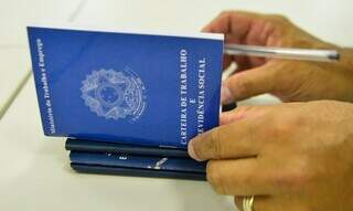 Pessoa assinando várias carteiras de trabalho (Foto: Marcello Casal Jr/Agência Brasil)