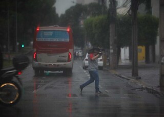 Homem atravessa avenida tentando se proteger da chuva (Foto: Henrique Kawaminami)