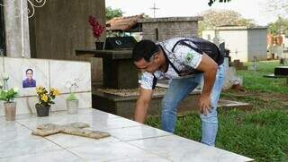 Gustavo limpando o túmulo do pai, no cemitério Santo Amaro (Foto: Alex Machado)