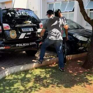 Momento em que suspeito foi chega na Deam, sendo conduzido por policial civil (Foto: Divulgação)