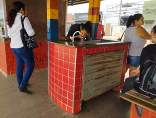Usuária do transporte público bebe água quente no Terminal Morenão, em Campo Grande. (Foto: Alison Silva)