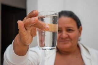 Mulher segurando copo de água na mão mostrando a transparência do produto (Foto: Paulo Francis)