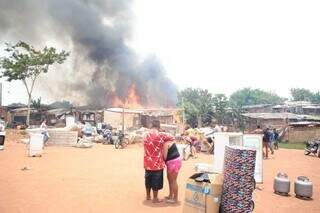 Moradores ao lado dos pertences retirados dos barracos durante o incêndio (Foto: Paulo Francis)