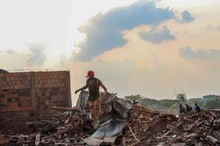 Morador busca materiais de construção que restaram após incêndio na favela do Mandela (Foto: Juliano Almeida)