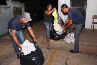 Voluntários separam sacos de roupas destinadas a doação. (Foto: Juliano Almeida)