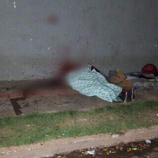 Corpo da vítima coberto na calçada e marcas de sangue. (Foto: Direto das Ruas)
