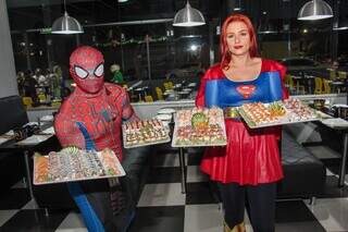 Os funcionários, vestidos de super-heróis, com as bandejas de sushi.