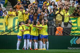 Jogadoras do Brasil comemorando gol da vitória e torcida ao fundo (Foto: Nayra Halm/Staff Images Woman/CBF)