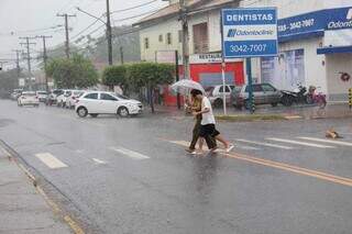 Pedestres dividindo um guarda-chuva para escapar da chuva, no Bairro Tiradentes (Foto: Juliano Almeida)