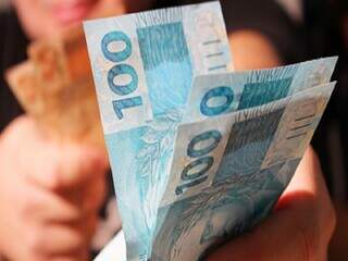 Várias cédulas de R$ 100 em uma mão (Foto: CNM)