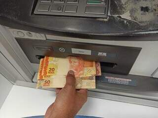 Notas de R$ 20 e R$ 50 sendo sacadas de caixa eletrônico (Foto: Arquivo/Campo Grande News)