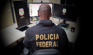 Policial federal verifica computadores durante operação. (Foto: Reprodução/PF)